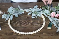 a wooden table topped with white beads and flowers