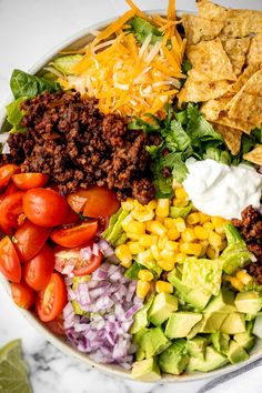 a bowl filled with taco salad, tortilla chips and avocado