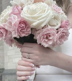 a woman holding a bouquet of pink and white flowers