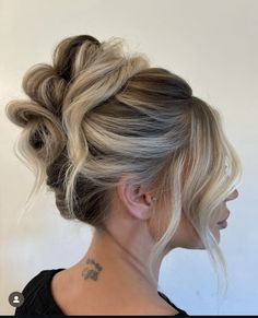 a woman with blonde hair styled into a low updo and tattoos on her neck