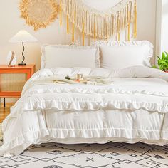 a bed with white sheets and pillows in a room next to a wall hanging on the wall