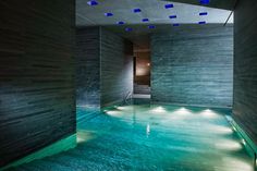 an indoor swimming pool with blue lights on the ceiling and water running down it's sides