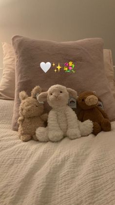 three stuffed animals sitting on top of a bed next to a pillow with hearts and stars