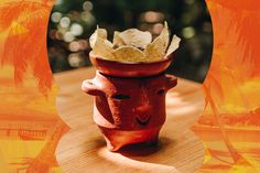 a clay pot with chips in it sitting on a wooden table next to palm trees