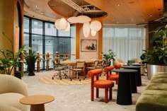 an office with tables, chairs and potted plants in the middle of the room