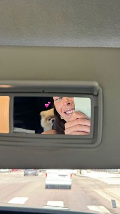 the reflection of a woman and her dog in a rear view mirror