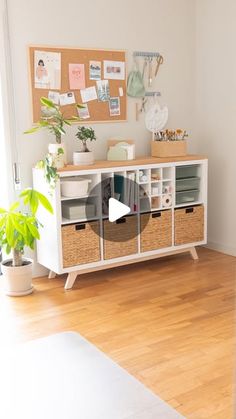 a living room with wooden floors and a white shelf filled with baskets on top of it