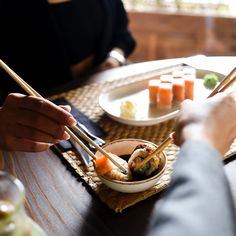 someone is eating sushi with chopsticks on the table