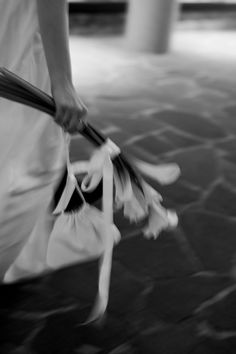 black and white photograph of a person walking with flowers in their hand on the sidewalk