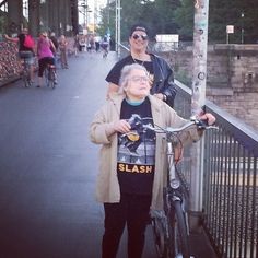 an older woman standing next to a man on a bike