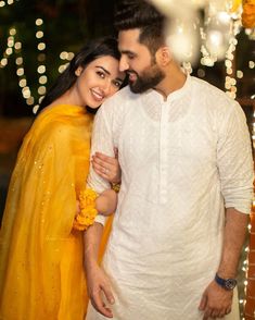 a man and woman standing next to each other with lights in the back ground behind them