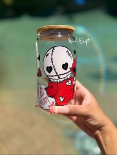 a person holding up a glass jar with an image on it