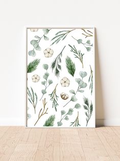 an art print with green leaves and pine cones on a white wall above a wooden floor