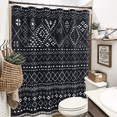 a bathroom with a black and white shower curtain next to a toilet in a room