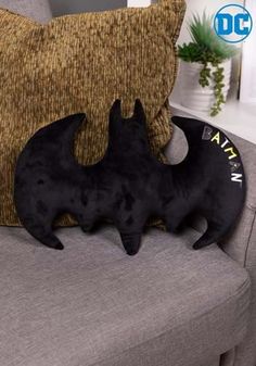 two black cat figurines sitting on top of a couch next to a pillow