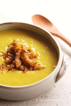 a white bowl filled with soup next to a spoon