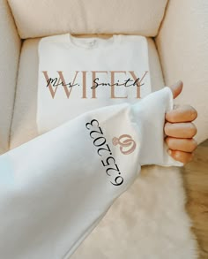 a woman's hand holding up a white t - shirt with the words wifey on it