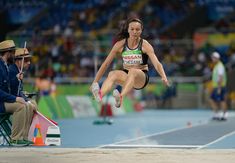 a woman jumping in the air on top of a track