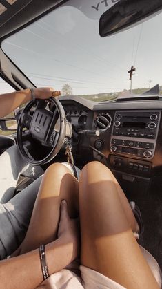 a woman sitting in the driver's seat of a car with her feet on the steering wheel