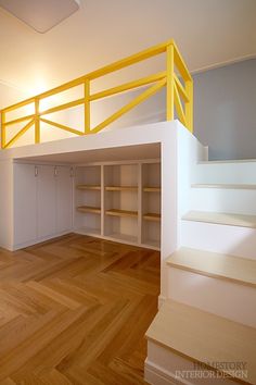 an empty room with white walls and yellow railings on the top floor, next to a set of stairs