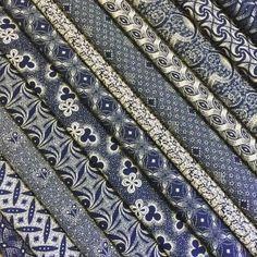 blue and white patterned ties are stacked together in rows on the table, with one being folded up