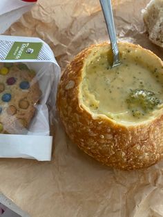 a bowl of broccoli soup next to a baguette with a cookie in it