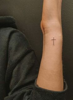 a woman's arm with a cross tattoo on the left side of her wrist