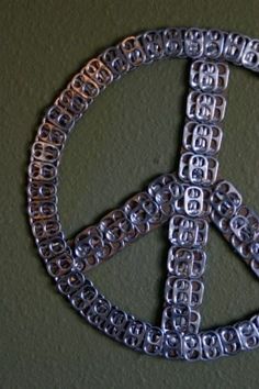 a peace sign made out of metal chains on a green wall with a black background