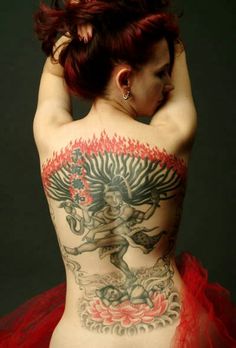 a woman with red hair and tattoos on her back is wearing a tutu skirt