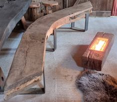 a wooden bench sitting next to a fire place on top of a cement floor covered in fur