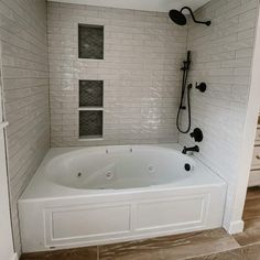 a white bath tub sitting inside of a bathroom next to a shower head and faucet