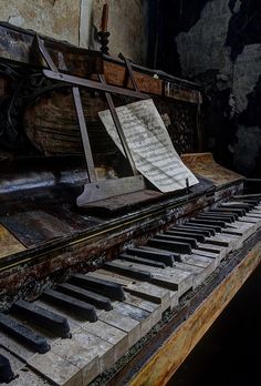 an old piano with sheet music sitting on it's side in a run down building