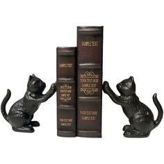 three black cat figurines sitting next to each other on top of two books