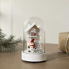 a snow globe with a house under it on a table next to a christmas tree