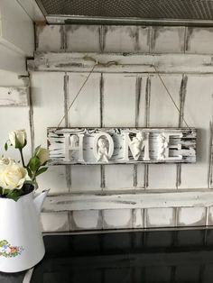 a white vase with flowers sitting on top of a counter next to a sign that says love