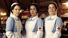 three women in white aprons standing next to each other with red cross on their chest