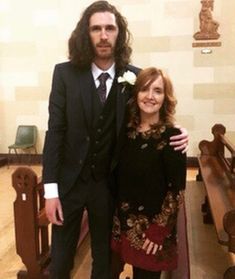 a man and woman standing next to each other in front of a church pews