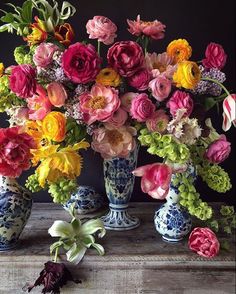 a vase filled with lots of colorful flowers on top of a wooden table next to other vases