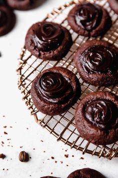 chocolate cookies cooling on a wire rack next to some nuts and cinnamon flecks