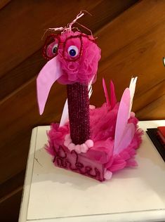 a pink bird made out of tissue paper sitting on top of a table