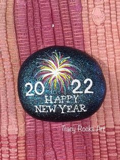 a rock with the words happy new year painted on it and fireworks in the sky