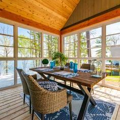 a table and chairs in a room with large windows on the side of the house