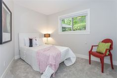 a bedroom with a white bed and red chair