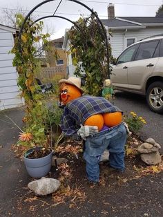 an orange scarecrow is in the middle of a garden with plants and potted plants