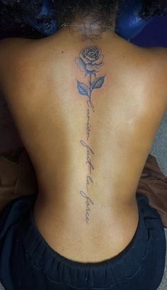 the back of a woman's neck has a rose tattoo on it and she is sitting down