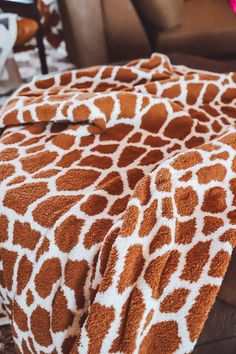 a giraffe print blanket sitting on top of a couch