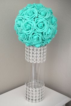 a vase filled with blue flowers on top of a white table next to a wall