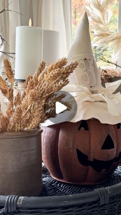 a pumpkin sitting on top of a table next to a potted plant and candles