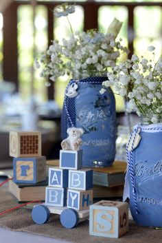 a blue mason jar filled with baby's breath flowers and blocks sitting on top of a table