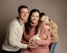 a man, woman and child are posing for a family photo with their newborn baby